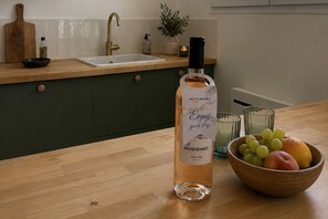 A kitchen with a wooden countertop, a bottle of Meridiennes wine, a bowl of fruit, and a potted plant. - Sanary Apt N1, Sanary-sur-Mer, France (Sanary-sur-Mer)