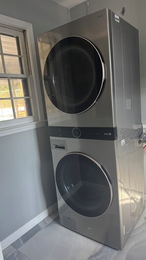 A stacked washer and dryer unit in a room with a window. - Spacious 4-bedroom house in fantastic Columbus with AC and gym access (Columbus)