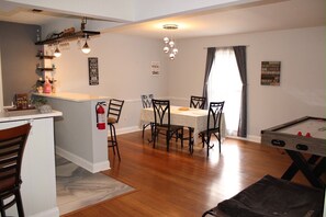 A dining area with a table and chairs, a kitchen with a counter and shelves, and a pool table. - Spacious 4-bedroom house in fantastic Columbus with AC and gym access (Columbus)