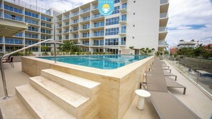 A modern hotel with a rooftop pool, outdoor seating, and a view of the surrounding buildings. - Jacana Sunset 205 | Bucerias Beach & Rooftop Infinity Pool (Bucerias)