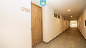 Corredor com porta de madeira identificada com o número '205', placa indicando 'KIVOYA Vacation Rentals' e vista para um quarto no final do corredor.
