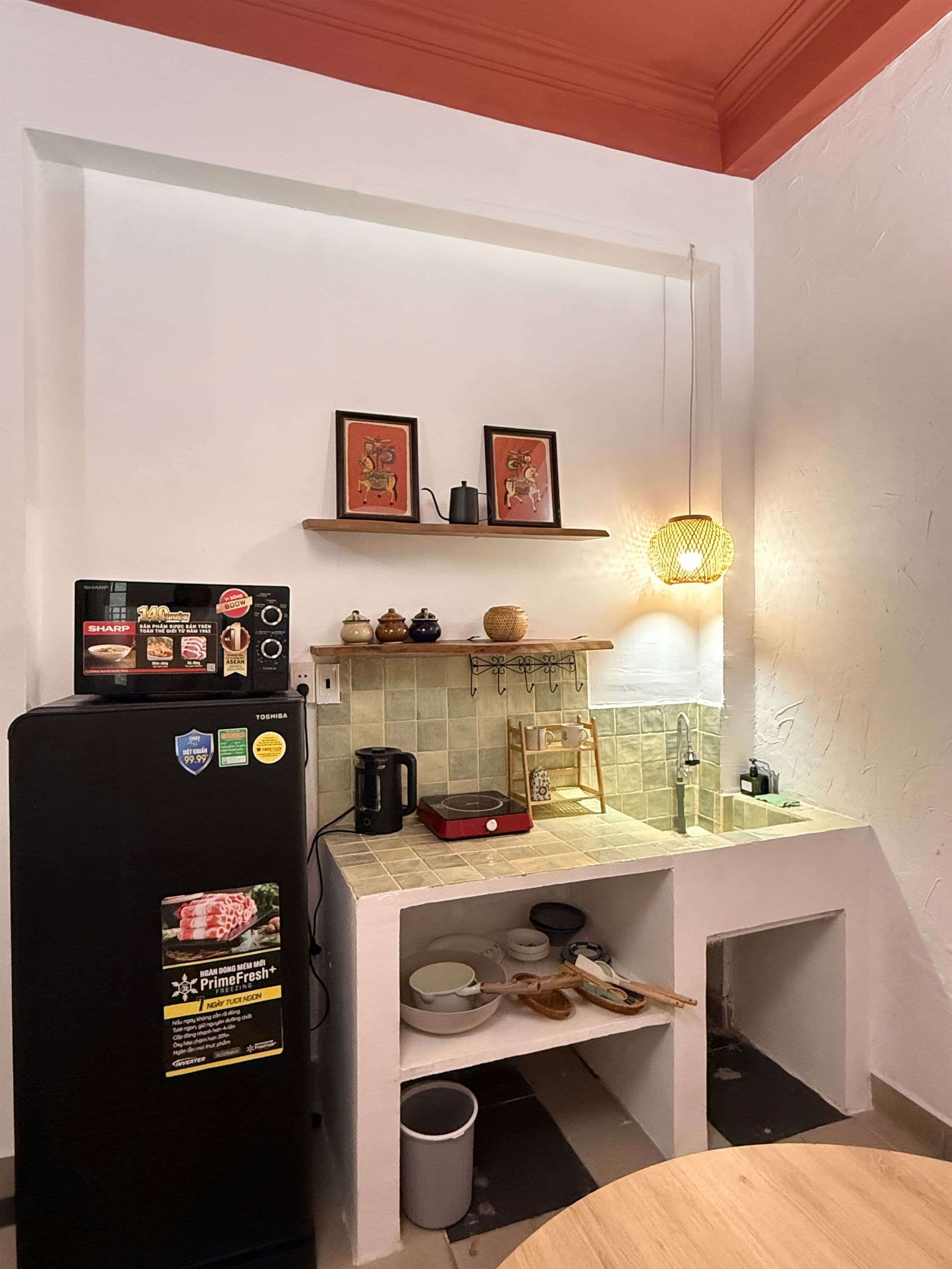 Una cucina compatta con frigorifero, forno a microonde, bollitore e lavandino.