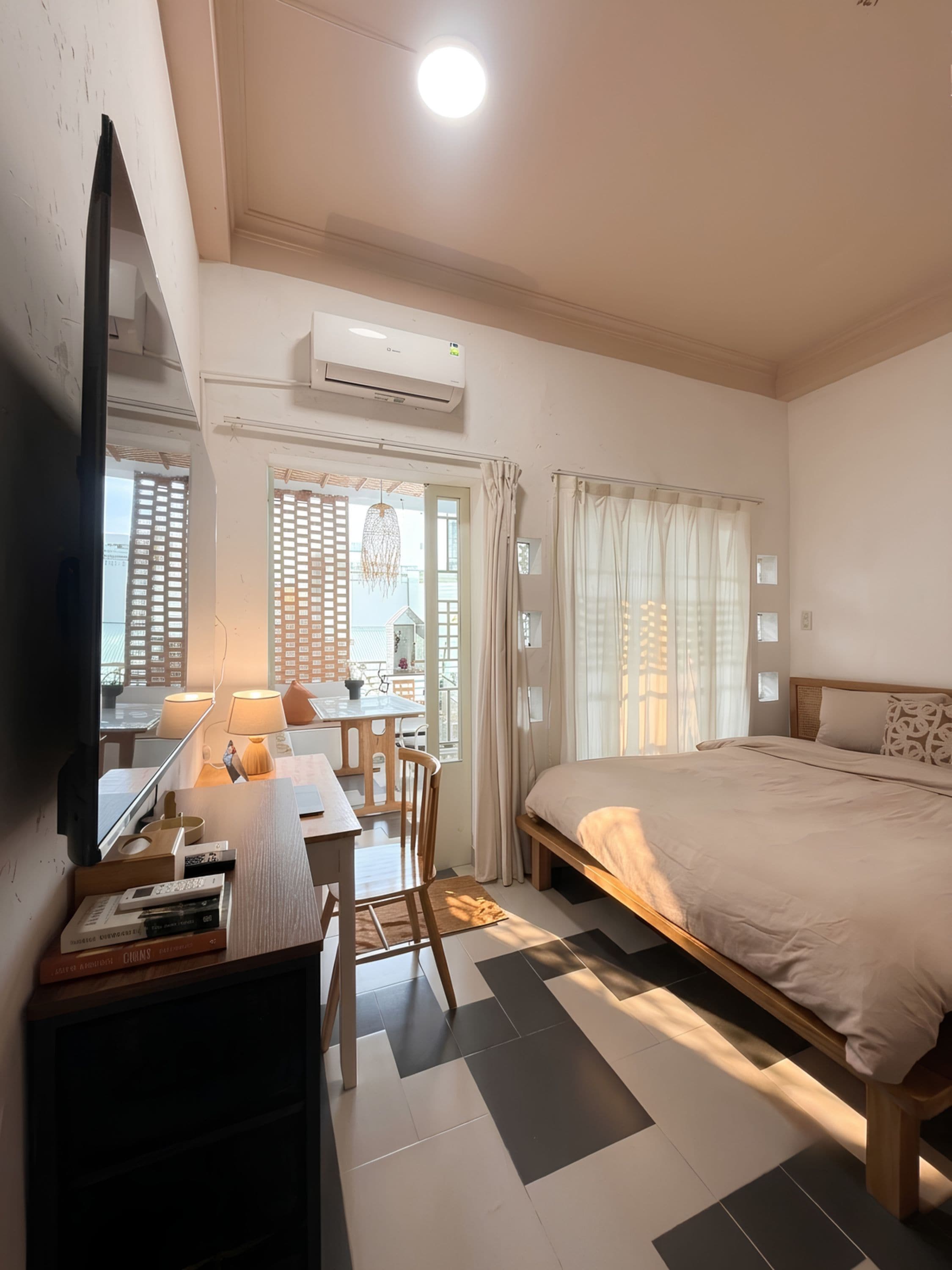 Un dormitorio con cama, escritorio, silla, televisor y aire acondicionado.