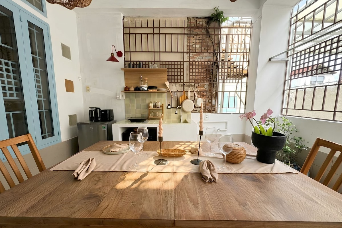 Un comedor con una mesa de madera, sillas y una planta en maceta.