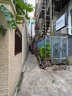 Un callejón estrecho con paredes de ladrillo, una reja metálica y una moto estacionada al costado.