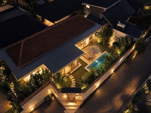 An aerial view of a residential property with a swimming pool, outdoor seating, and well-lit areas. - Dimora Bali Residence (Badung)