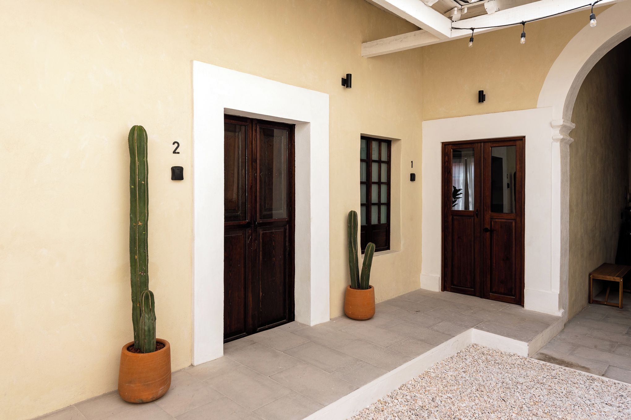 A hallway with three doors, numbered 1, 2, and 3, and two potted cacti.