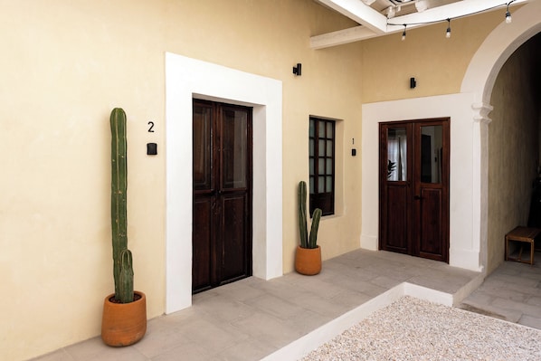 A hallway with three doors, numbered 1, 2, and 3, and two potted cacti. - Hidalgo By Homirent (Santiago de Querétaro)