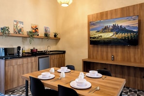 Una cocina moderna con comedor, un televisor de pantalla plana en la pared y un cuadro sobre el televisor.