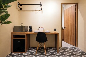 A compact room with a wooden desk, a black office chair, a microwave, a small cabinet, and a door leading to another room. - Hidalgo By Homirent (Santiago de Querétaro)