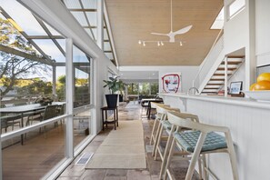 Ein modernes Interieur mit einem langen Essbereich, einer Treppe und Blick ins Freie.