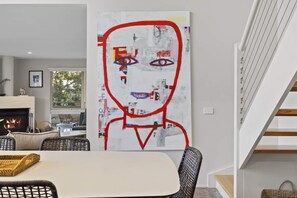 A modern living room with a fireplace, a dining area, and a staircase. - Sullivan's Loft (Sorrento)