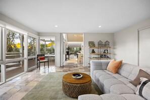 A spacious living area with a grey sofa, a round wooden coffee table, and a bookshelf. - Sullivan's Loft (Sorrento)