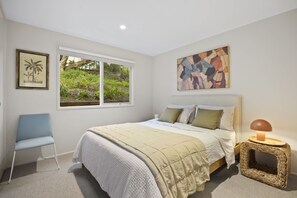 Ein Schlafzimmer mit einem Bett, einem Sessel, einem Fenster und Bildern an den Wänden.