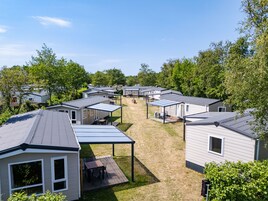 A row of mobile homes with attached patios and a grassy yard.