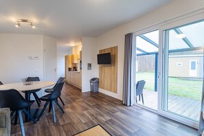 Un intérieur moderne comprenant un coin repas, une cuisine et une grande porte-fenêtre coulissante donnant sur une terrasse.
