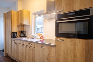 Una cocina moderna con armarios de madera, horno empotrado y cafetera.