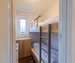 Habitación pequeña con literas, una ventana, un escritorio y un armario.