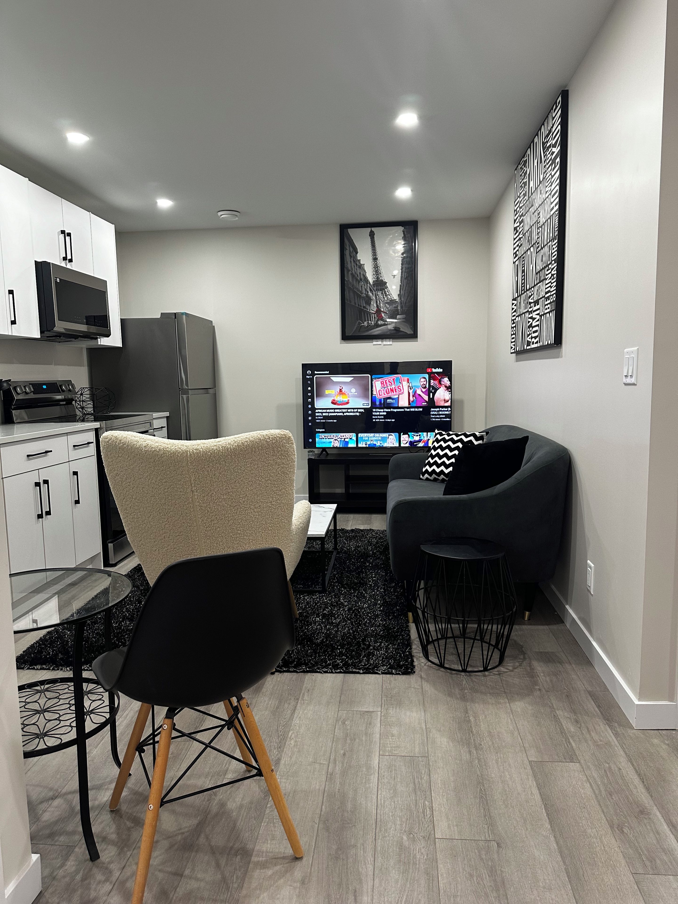 A modern living room with a flat-screen TV, a sofa, and a dining area with a glass table and chairs.