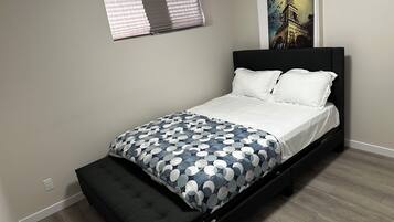 Quarto com uma cama, uma janela e um quadro da Torre Eiffel.