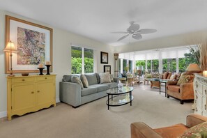 A spacious living room with a sofa, armchairs, a coffee table, and a yellow cabinet. - Olde Naples Getaway | 2BR Condo Near Beach & 3rd Ave S (Naples)