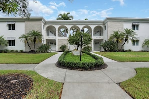 A building with a symmetrical facade, multiple balconies, and a central landscaped area with a statue. - Olde Naples Getaway | 2BR Condo Near Beach & 3rd Ave S (Naples)