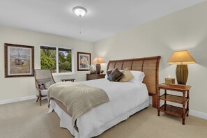 A bedroom with a large bed, two bedside tables with lamps, a chair, and artwork on the walls. - Olde Naples Getaway | 2BR Condo Near Beach & 3rd Ave S (Naples)