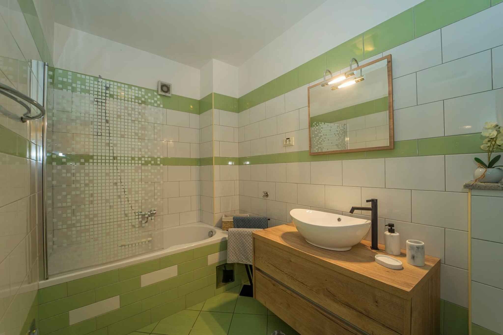 A bathroom with a glass shower enclosure, a freestanding bathtub, and a vanity with a sink and mirror.