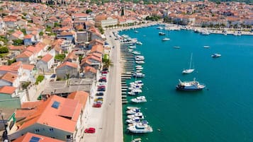 A coastal town with a marina filled with boats, a beach, and buildings with red-tiled roofs.