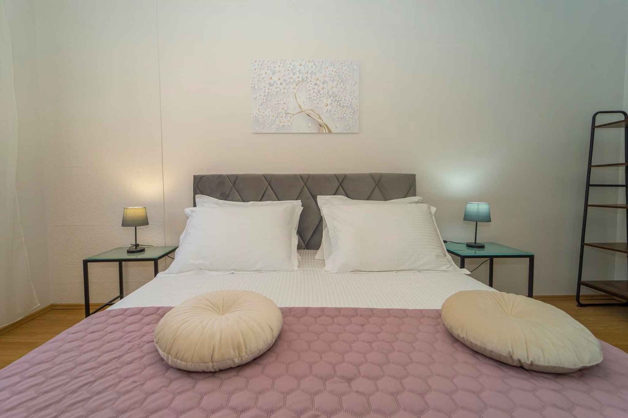 A bedroom with a bed, two bedside tables, a wall-mounted artwork, and a ladder.