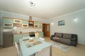 A compact kitchen with a dining area, a grey sofa, and a small side table. - Holiday apartment with air conditioning and terrace (Vela Luka)