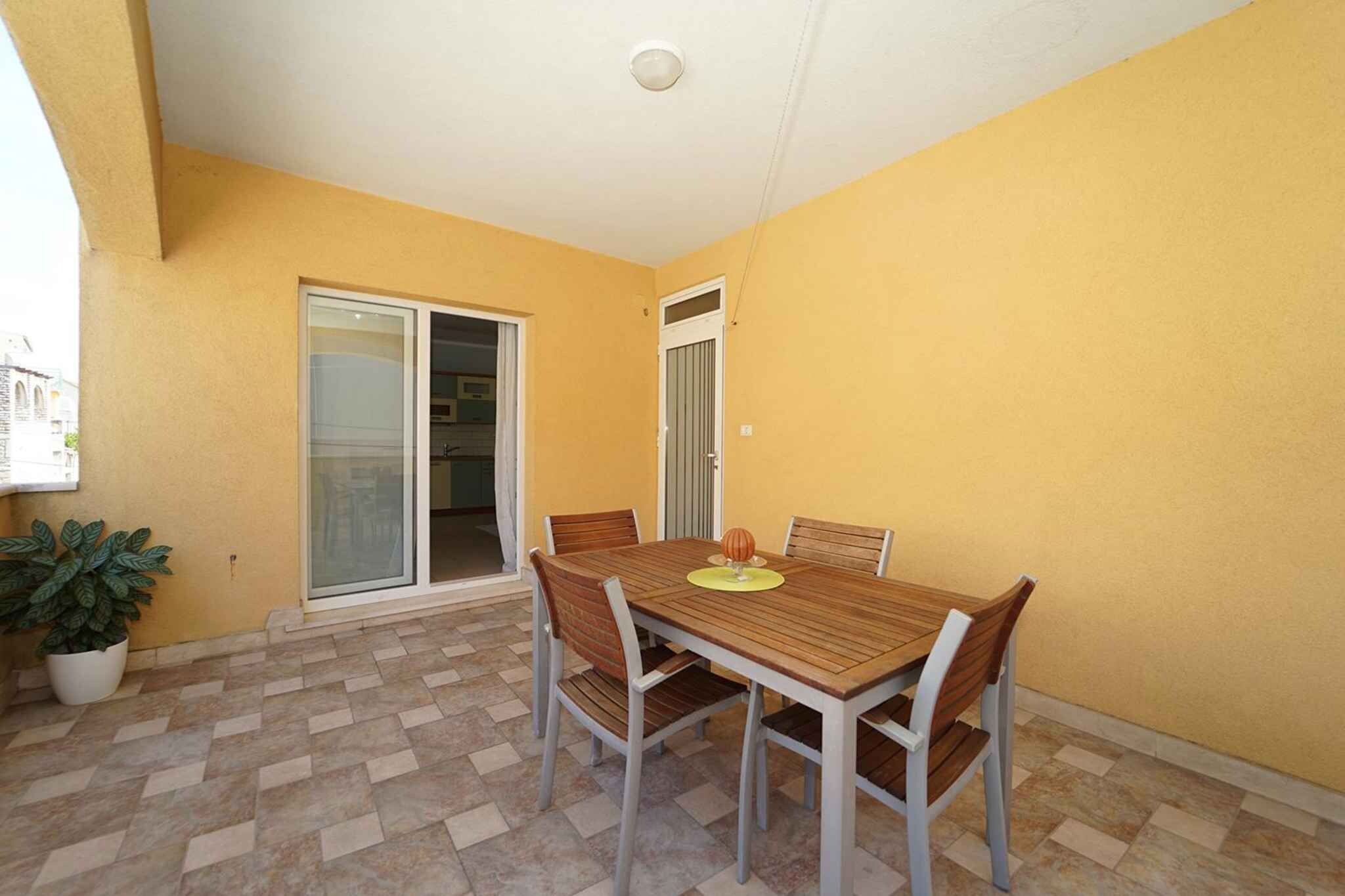 A dining area with a table and chairs, a potted plant, and a sliding glass door leading to a kitchen.