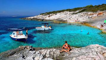 A coastal scene with clear turquoise waters, rocky terrain, and boats.