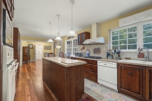 A kitchen with wooden cabinets, a central island, and a window providing natural light. - Cedar Vista | Mt. Yonah Views & Pool Table (Sautee Nacoochee)