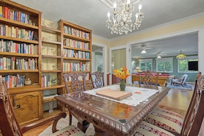 A spacious room with a large wooden bookcase filled with books, a dining table with chairs, and a chandelier. - Cedar Vista | Mt. Yonah Views & Pool Table (Sautee Nacoochee)