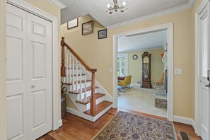 A hallway with a wooden staircase, a patterned rug, and a large wall clock. - Cedar Vista | Mt. Yonah Views & Pool Table (Sautee Nacoochee)