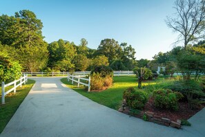 A paved pathway leading through a park with white fences and lush greenery. - Cedar Vista | Mt. Yonah Views & Pool Table (Sautee Nacoochee)