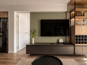 Uma sala de estar moderna com uma televisão de tela plana, um móvel de madeira escura e uma planta.