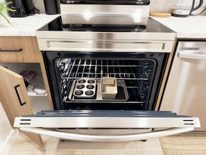 Un four ouvert, avec une plaque de cuisson et des moules à muffins à l’intérieur.