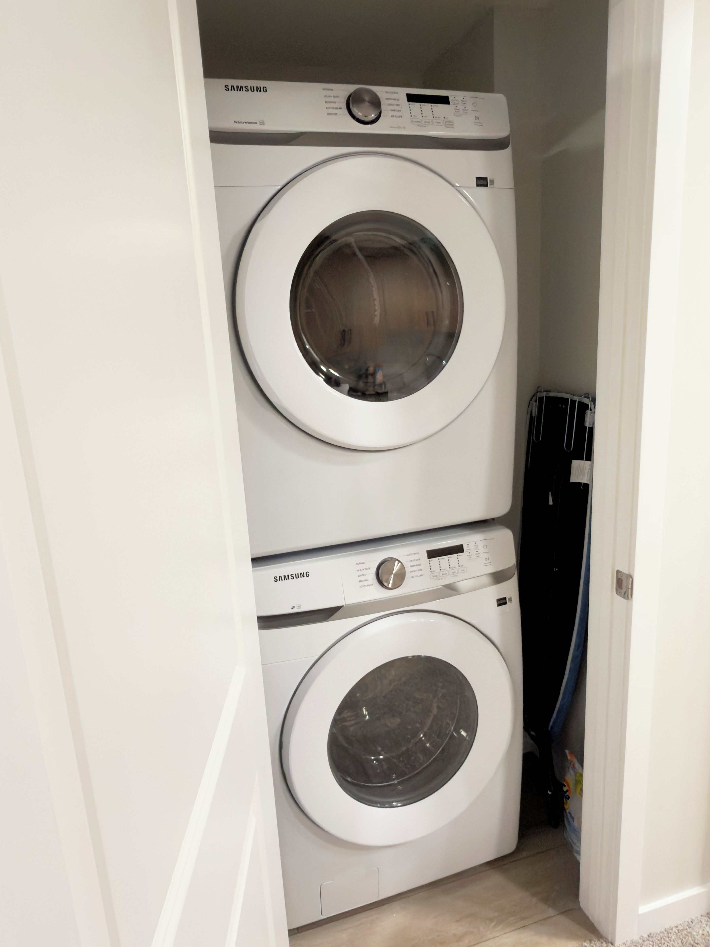A Samsung front-loading washer and dryer stacked in a narrow hallway.