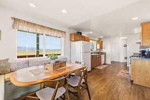 A kitchen with wooden cabinets, a built-in refrigerator, and a dining area with a bench and chairs.