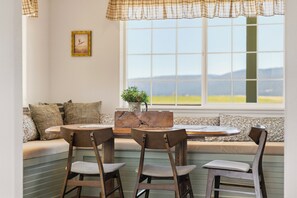 A dining area with a table and chairs, a window with a view, and a sofa with cushions. - Bird Watcher’s Retreat • 215 Acres • Water Views (Bonanza)