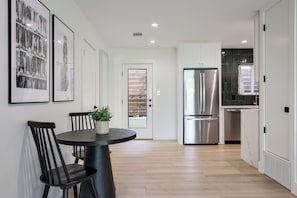 A modern kitchen with a stainless steel refrigerator, a dining area with a round table and chairs, and a hallway with a door leading to another room. - Chic 2BR on South Congress / Private Backyard (Austin)
