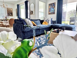 Ein Wohnzimmer mit einem blauen Sofa, einem Kaktus und einer weißen Blumenkomposition.