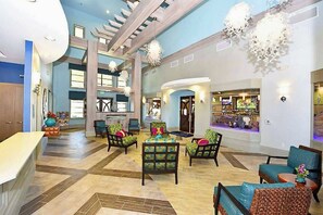 Un hall d’entrée spacieux avec un plafond haut, de nombreux espaces de détente et un bar/salon.