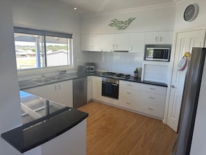 Una cocina moderna con armarios blancos, encimera negra y refrigerador de acero inoxidable.