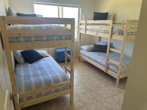 A room with two bunk beds, each with a mattress and pillows, and a blue storage bin. - Sea Breeze Beach House -
 Entire home in Dongara (Dongara)