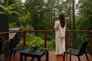 Una persona de pie en una cubierta de madera con vista a un área boscosa.
