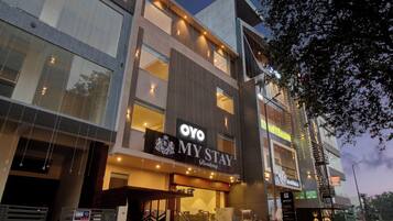 Un hotel moderno con un llamativo letrero 'OYO MY STAY', varios pisos y una escalera que conduce a la entrada.