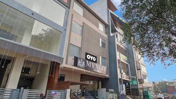 Un edificio de varios pisos con un llamativo letrero de 'OYO MYSTAY' en la planta baja.